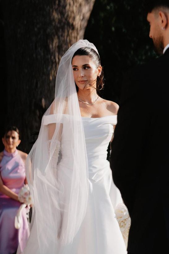 Sposa alla cerimonia, velo lungo su chignon liscio